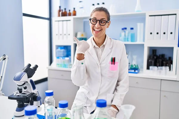 Young Woman Working Scientist Laboratory Pointing Thumb Side Smiling Happy — Stock Photo, Image