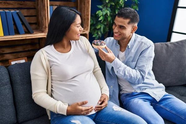 Young Latin Couple Expecting Baby Eating Doughnut Home — Stock Photo, Image