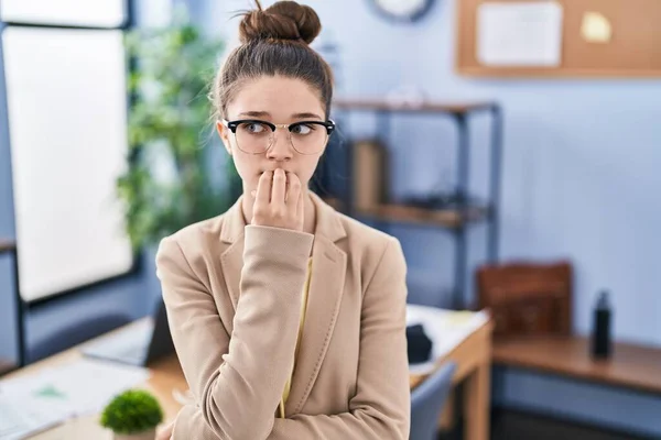 在办公室工作的少女戴着眼镜 双手放在咬指甲的嘴上 看上去很紧张 很紧张 焦虑问题 — 图库照片