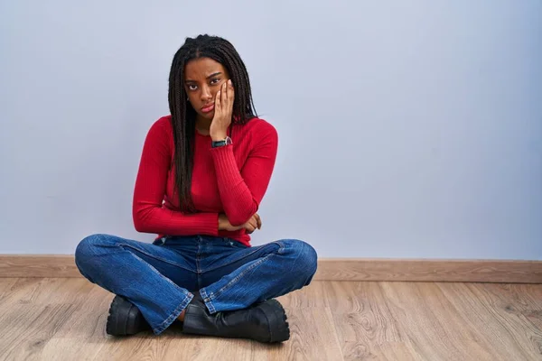 Młody Afroamerykanin Warkoczami Siedzący Podłodze Domu Myśląc Wygląda Zmęczonego Znudzonego — Zdjęcie stockowe
