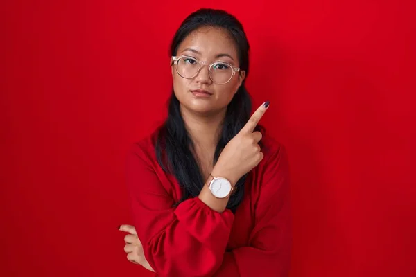 Asyalı Genç Bir Kadın Kırmızı Arka Planda Duruyor Parmağı Yanda — Stok fotoğraf
