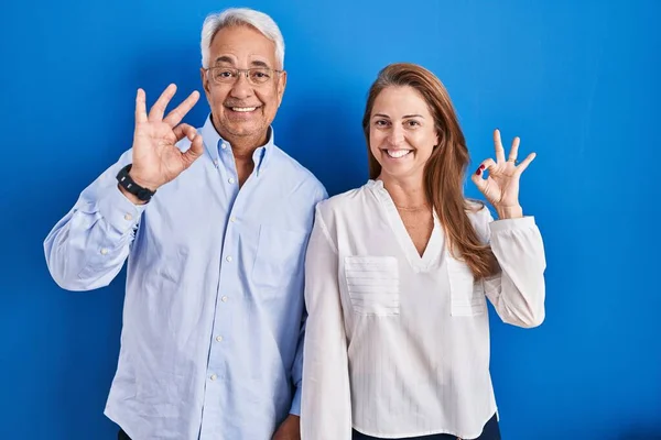 Middelbare Leeftijd Hispanic Paar Staan Blauwe Achtergrond Lachend Positief Doen — Stockfoto