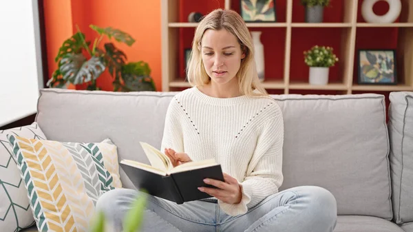Young Blonde Woman Reading Book Sitting Sofa Home — Photo