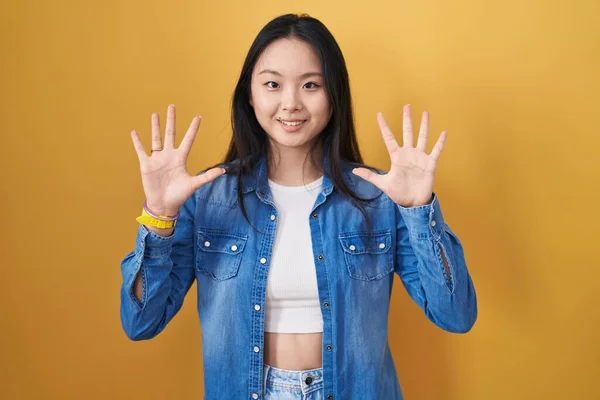 Молодая Азиатка Стоящая Жёлтом Фоне Показывающая Пальцами Номер Десять Улыбаясь — стоковое фото