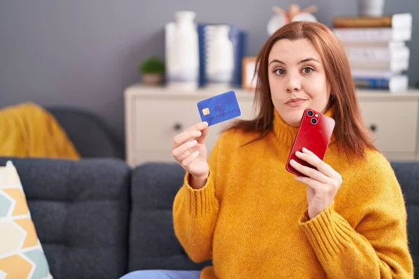 Young Beautiful Size Woman Using Smartphone Credit Card Doubt Expression — Stockfoto