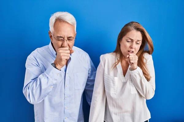中年时 他的一对惊慌失措的夫妇站在蓝色的背景上 感觉不舒服 咳嗽是感冒或支气管炎的症状 保健概念 — 图库照片