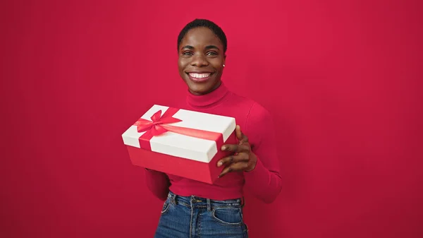 Donna Afroamericana Sorridente Fiducioso Tenendo Regalo Compleanno Sfondo Rosso Isolato — Foto Stock