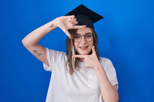 卒業キャップを被った金髪の白人女性が幸せな顔で手や指でフレームを作り笑顔 創造性と写真の概念 — ストック写真