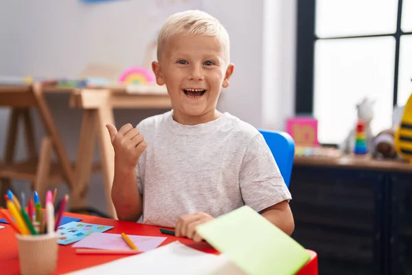 Menino Caucasiano Pintando Escola Apontando Polegar Para Lado Sorrindo Feliz — Fotografia de Stock
