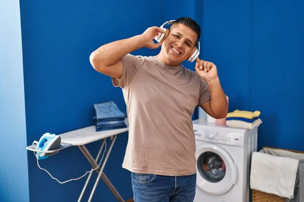 在洗衣房听音乐等洗衣机的年轻拉丁男人 — 图库照片