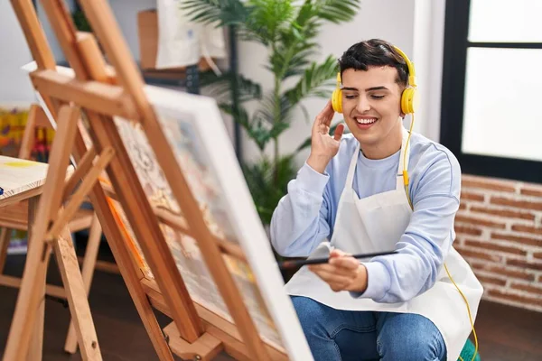 Sanat stüdyosunda müzik dinleyen genç, ikili olmayan bir sanatçı.