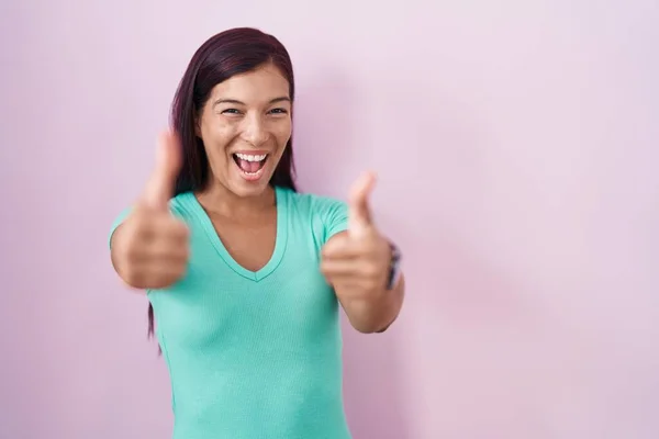 Молода Іспаномовна Жінка Стоїть Над Рожевим Тлом Схвалюючи Позитивний Жест — стокове фото