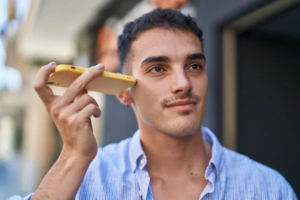若いヒスパニック系の男笑顔自信を持ってリスニング音声メッセージによってスマートフォンでストリート — ストック写真