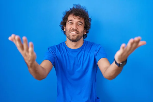 Hispánec Mladý Muž Stojící Nad Modrým Pozadím Úsměvem Veselá Nabídka — Stock fotografie