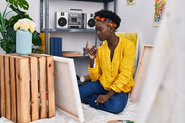 Genç Afrikalı Amerikalı kadın ressam sanat stüdyosunda şüpheli bir ifadeyle çizim yapıyor.