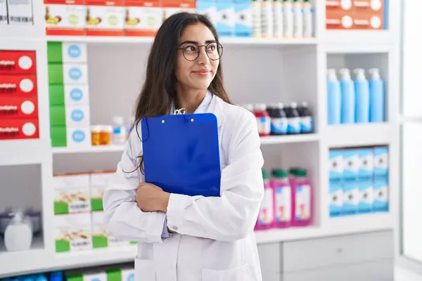 Young Hispanic Girl Pharmacist Hugging Clipboard Pharmacy — Zdjęcie stockowe