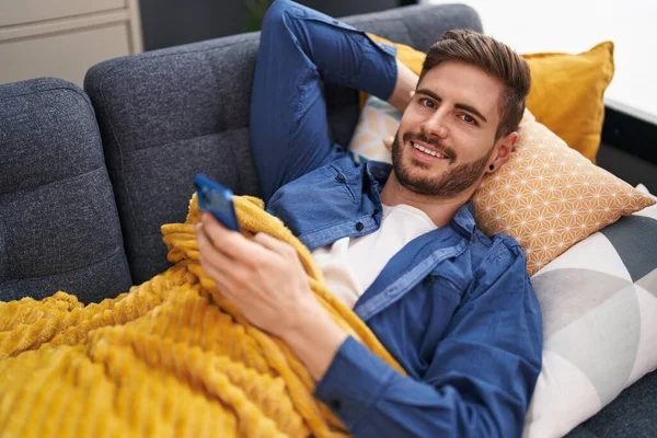 Young Caucasian Man Using Smartphone Lying Sofa Home — Stok fotoğraf