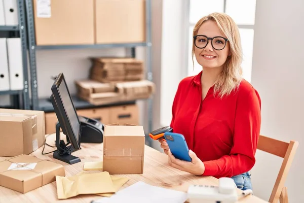 Young Blonde Woman Ecommerce Business Worker Scanning Package Using Smartphone — Zdjęcie stockowe