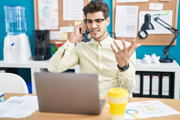Young Hispanic Man Business Worker Using Laptop Talking Smartphone Office — Foto Stock