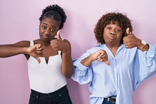 Two African Women Standing Pink Background Doing Thumbs Disagreement Agreement — Stock Photo, Image