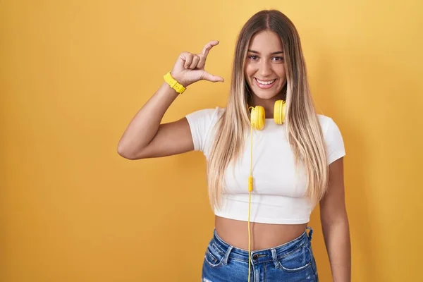 Mujer Rubia Joven Pie Sobre Fondo Amarillo Con Auriculares Sonrientes — Foto de Stock