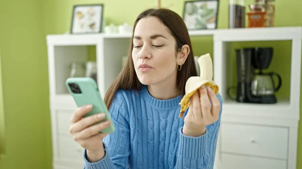 Joven Mujer Caucásica Comiendo Plátano Usando Smartphone Comedor —  Fotos de Stock