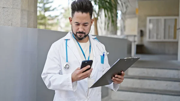 Jovem Latino Homem Médico Usando Smartphone Segurando Prancheta Hospital — Fotografia de Stock