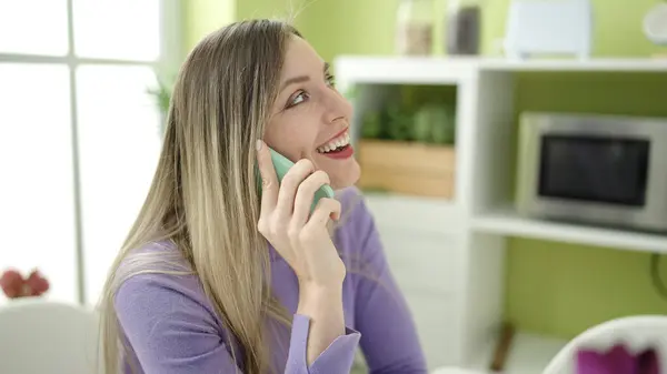 Genç Sarışın Kadın Akıllı Telefondan Konuşuyor Evde Masada Oturuyor — Stok fotoğraf
