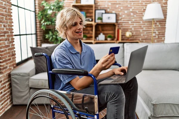 Молодой Блондин Использующий Ноутбук Кредитную Карту Сидит Дома Инвалидной Коляске — стоковое фото