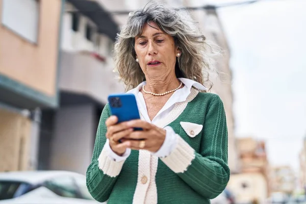スマートフォンを路上で使う中年女性 — ストック写真