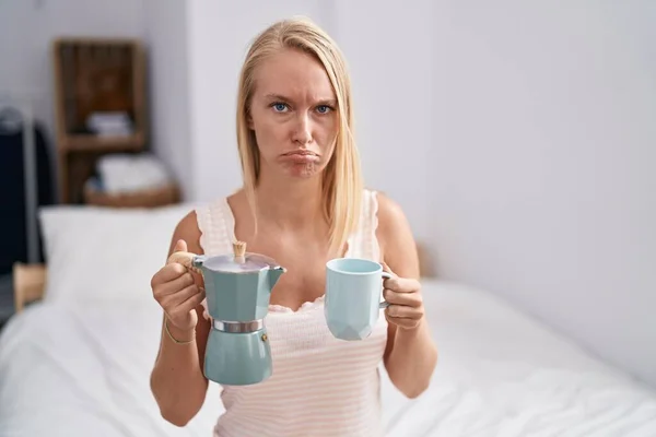 若い白人女性はベッドの上でコーヒーを飲んで落ち込んでおり 苦痛のために心配し 怒って恐れて泣いています 悲しい表情 — ストック写真