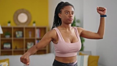 Evde spor kıyafeti giyen Afrikalı Amerikalı bir kadın.
