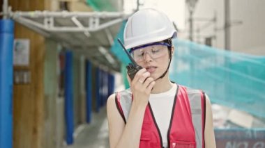 Güzel İspanyol kadın müteahhit sokakta telsizle konuşuyor.