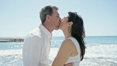 Kıdemli erkek ve kadın çift deniz kenarında öpüşüyorlar.