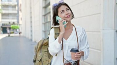 Genç, güzel İspanyol kadın turist akıllı telefondan konuşuyor. Sokakta kahve içiyor.