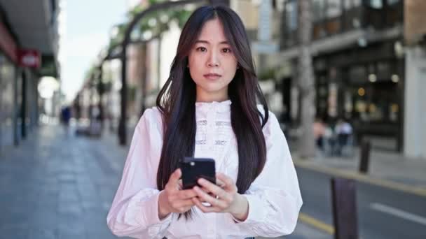 Junge Chinesin Lächelt Mit Smartphone Auf Der Straße — Stockvideo