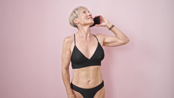Middle Age Blonde Woman Wearing Bikini Talking Smarpthone Isolated Pink — Stock Video