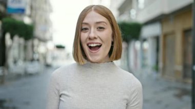 Young blonde woman standing with surprise expression at street