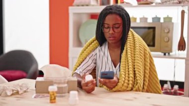 Afro-Amerikalı bir kadın yemek odasında hap arıyor.