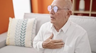 Yaşlı, kır saçlı adam, evinde kalp krizi geçiriyor.