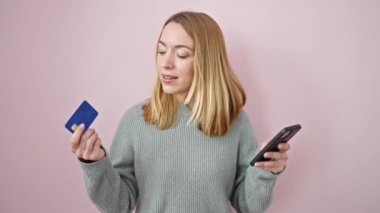 Akıllı telefon ve kredi kartıyla alışveriş yapan genç sarışın bir kadın.