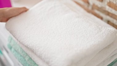 Genç ve güzel İspanyol kadın çamaşır odasında katlanmış havlulara dokunuyor.