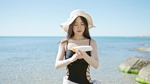 年轻的中国女性游客带着自信的笑容在海滨涂防晒霜 — 图库视频影像