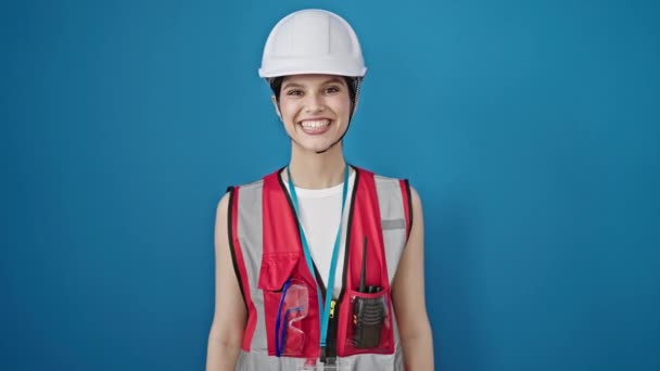 惊慌失措的女建筑工人微笑着 自信地站在孤立的蓝色背景之上 — 图库视频影像