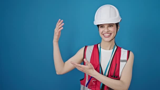 年轻美丽的惊慌失措的女建筑工人带着自信的笑容 呈现在孤独的蓝色背景上 — 图库视频影像