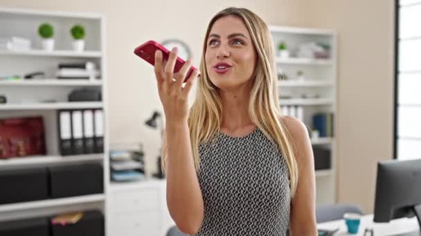 若いブロンドの女性のビジネスワーカーは オフィスで働くスマートフォンによって音声メッセージを送信 — ストック動画