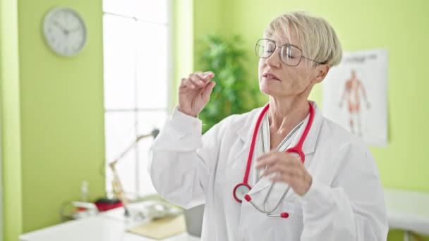 Blondynka Średnim Wieku Lekarz Stoi Poważnym Wyrazem Twarzy Wyjmując Okulary — Wideo stockowe