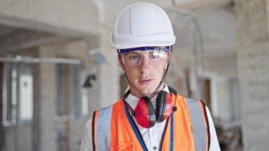 Kafkasyalı genç mimar inşaat alanında kendine güvenerek gülümsüyor.