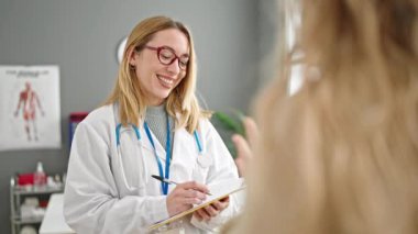 Genç sarışın kadın doktor klinikte tıbbi danışmanlık yapıyor.