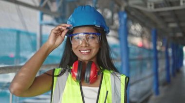 Afro-Amerikalı kadın inşaatçı gülümseyerek sokakta duruyor.